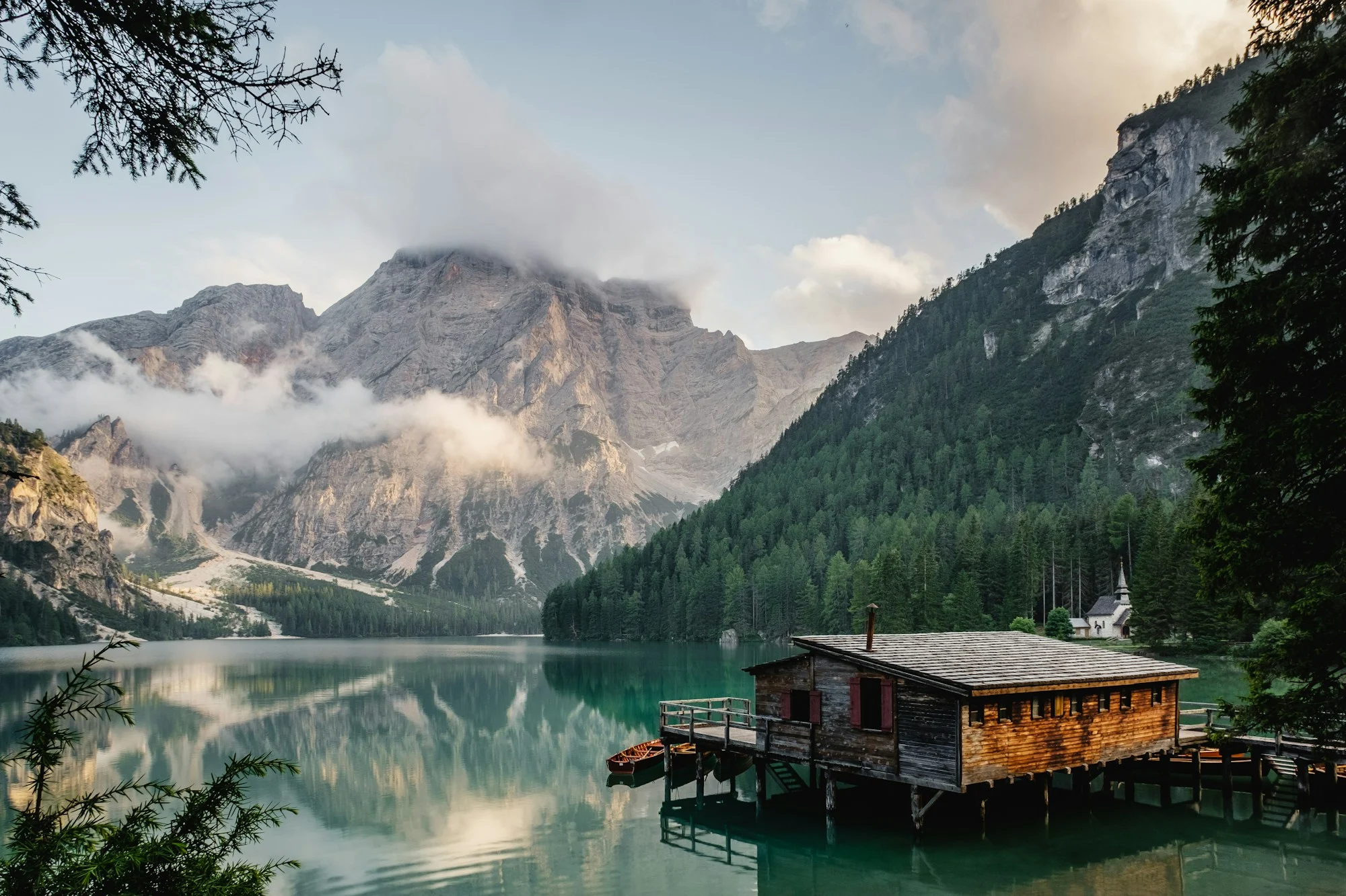 A peaceful alpine lake reflecting woodland and a lakeside house